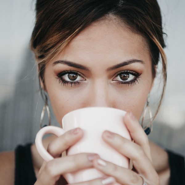 woman drinking from white coffee cup