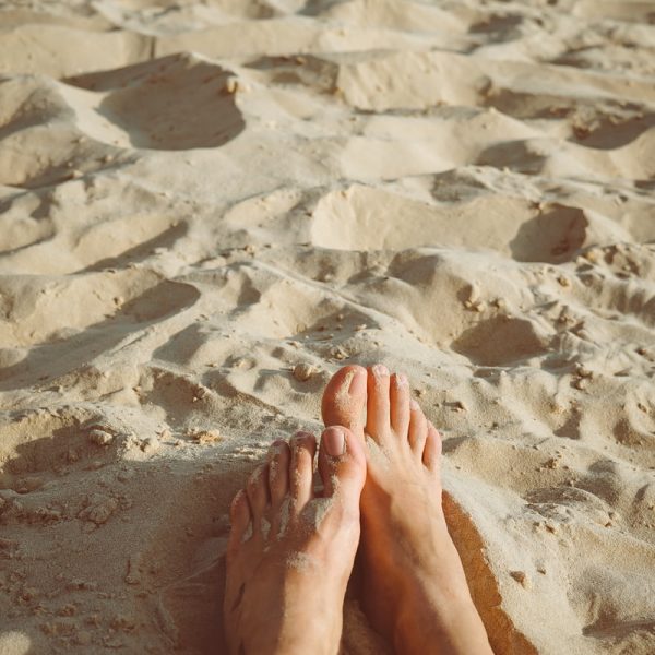 person's feet lying on sand